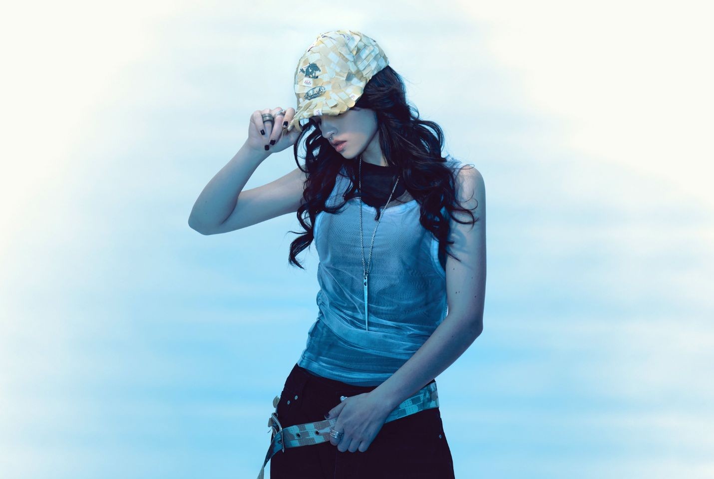 Ari Abdul wearing black trousers, a white vest, and a cap